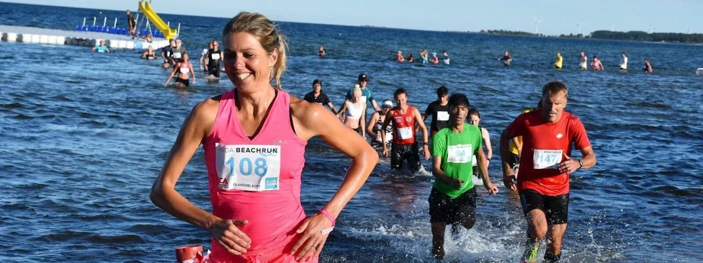 Löpare i Böda Beachrun springer genom vattnet.  Kul!