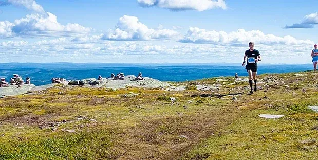 Löpare springer på en fjällväg med utsikt över bergen.