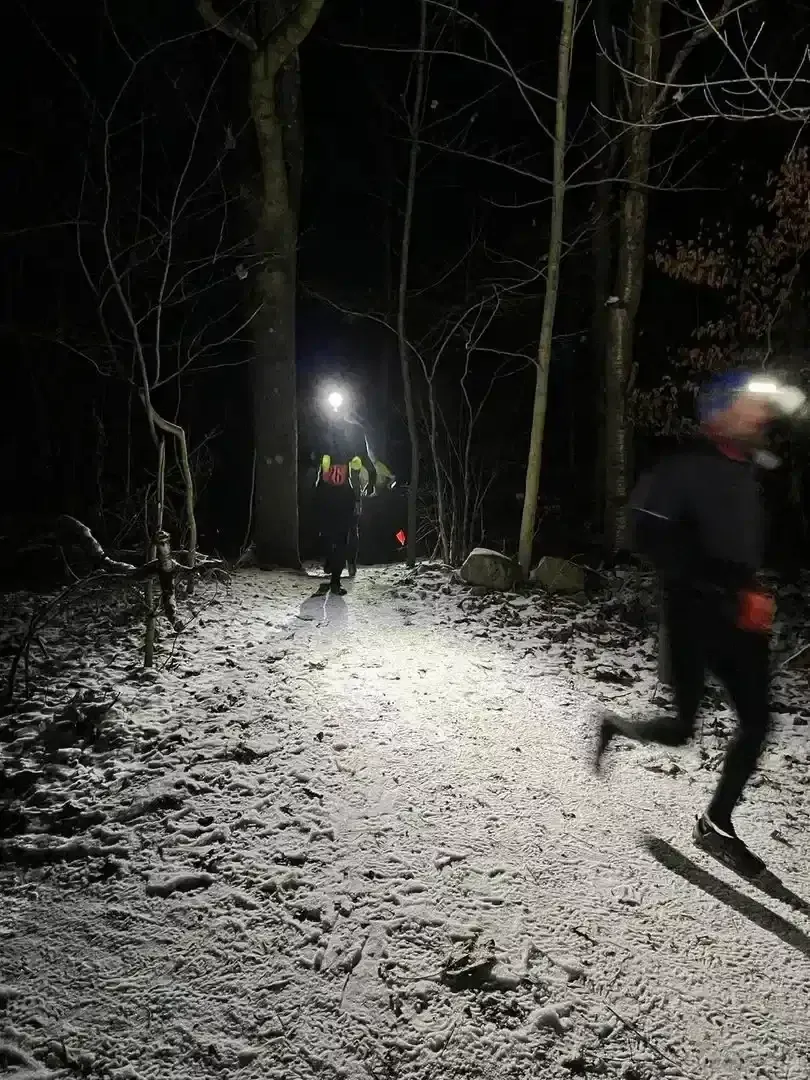 Löpare på en snöig stig under nattens lopp.