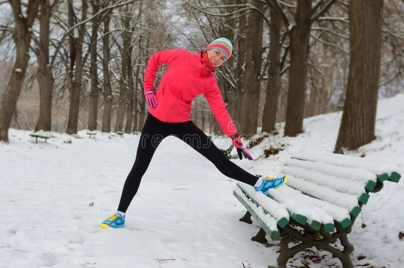 Kvinna stretchar inför Vinterspringet i snöig park.